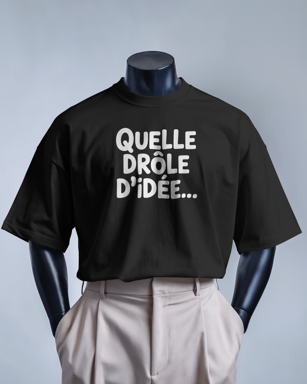 T-shirt MerciSidi "Quelle drôle d'idée..." avec impression humoristique, porté sur mannequin avec pantalon classique et costume ajusté.